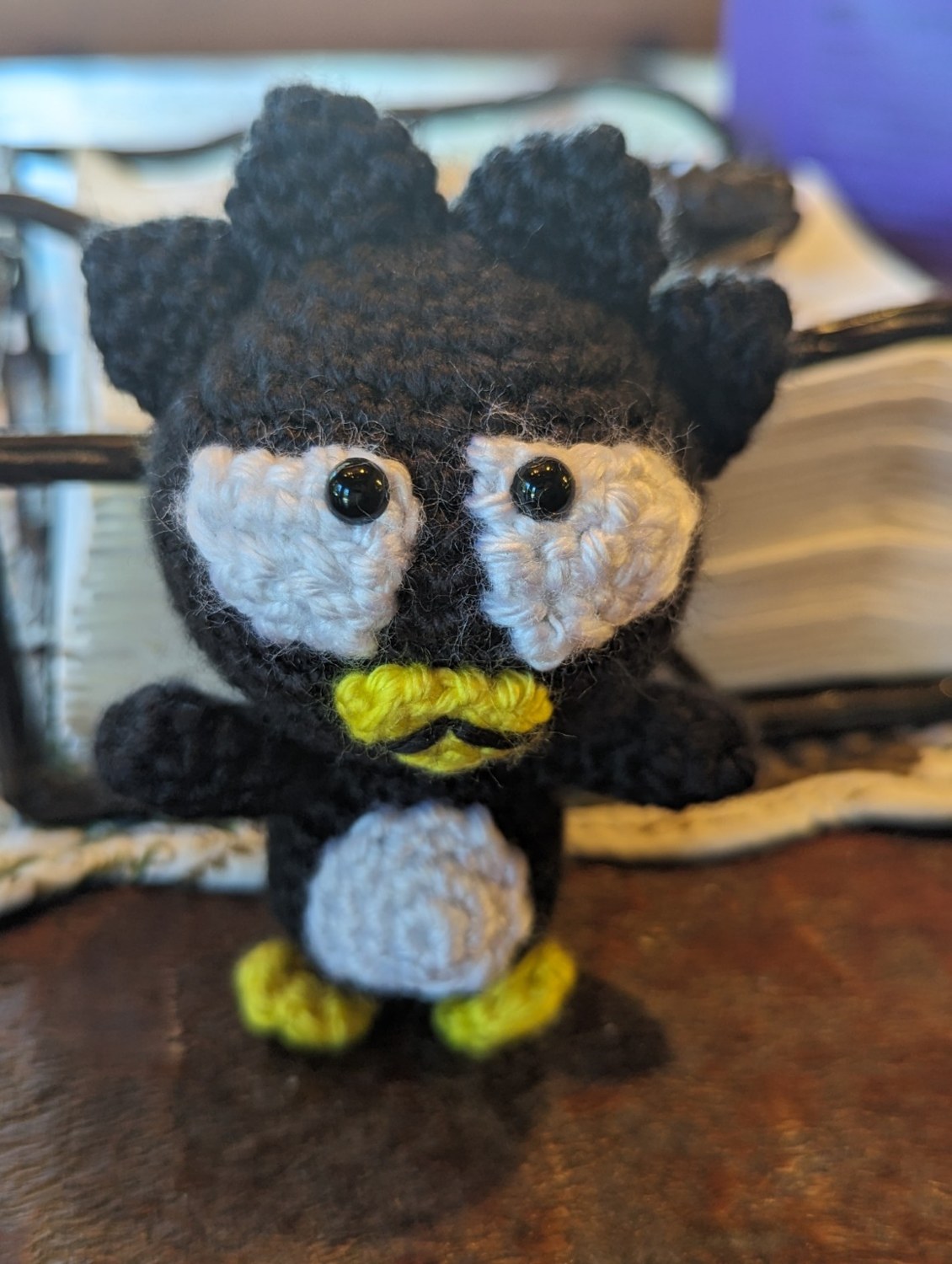 Handmade Badtz-Maru crochet penguin with spiky black hair, white eyes and belly, and a yellow beak and feet